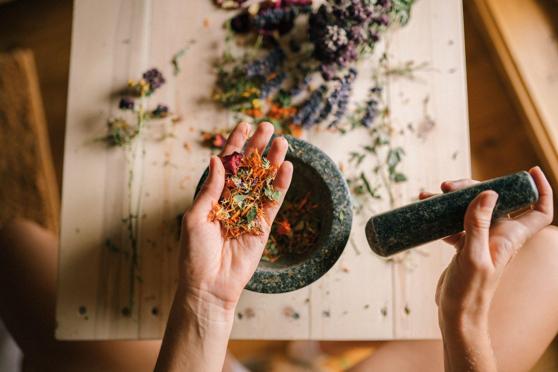 Hands grinding dried flowers in a mortar