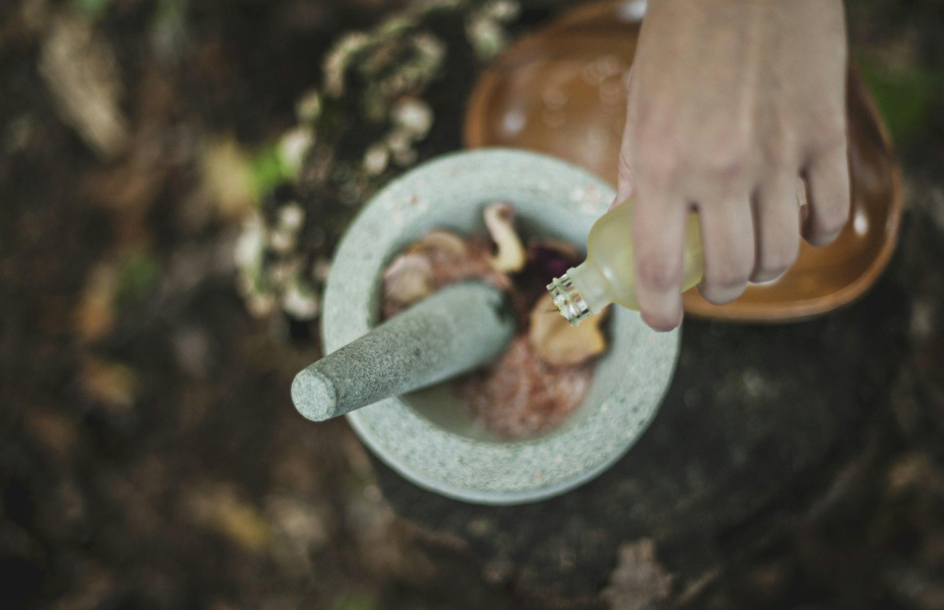 Hand pouring oil into a stone mortar