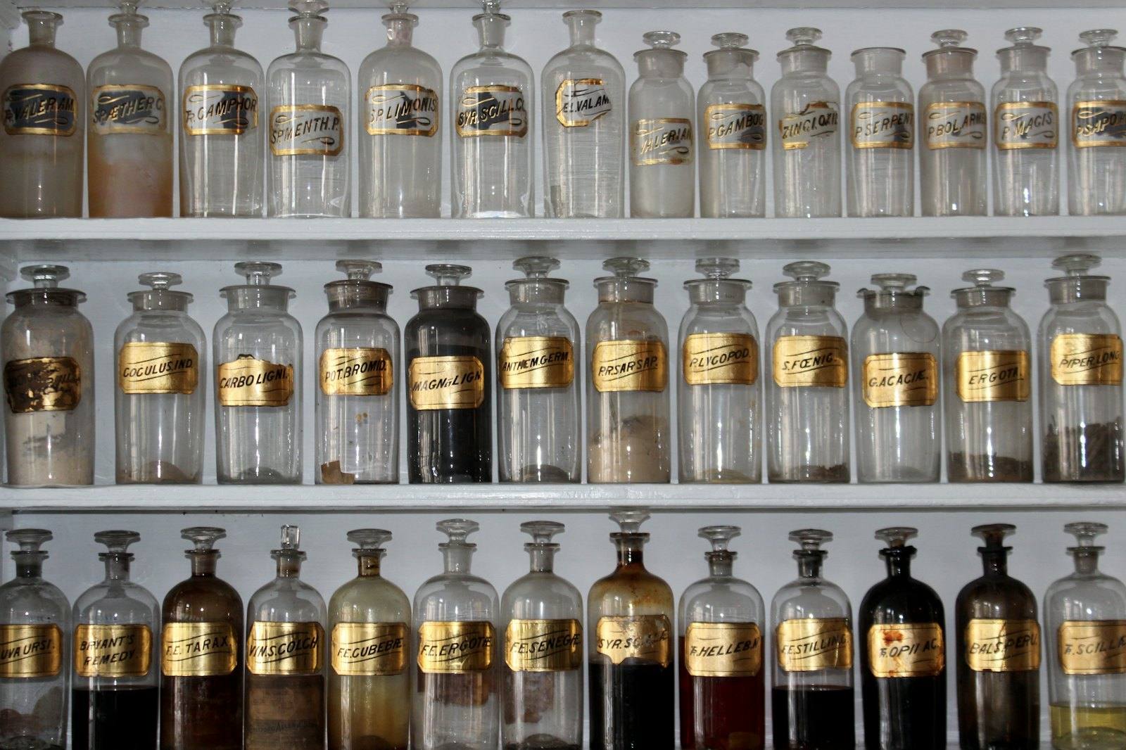 Rows of glass apothecary jars on white shelves